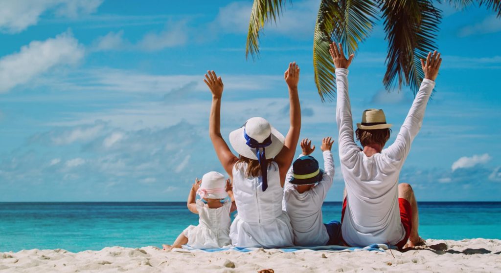 Family with arms up on beach holiday